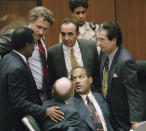 FILE- Defendant O.J. Simpson is surrounded by his defense attorneys, from left, Johnnie L. Cochran Jr., Peter Neufeld, Robert Shapiro, Robert Kardashian, and Robert Blasier, seated at left, at the close of defense arguments in his murder trial, Thursday, Sept. 28, 1995, in Los Angeles. Simpson, the decorated football superstar and Hollywood actor who was acquitted of charges he killed his former wife and her friend but later found liable in a separate civil trial, has died. He was 76. (Sam Mircovich/Pool Photo via AP, File)