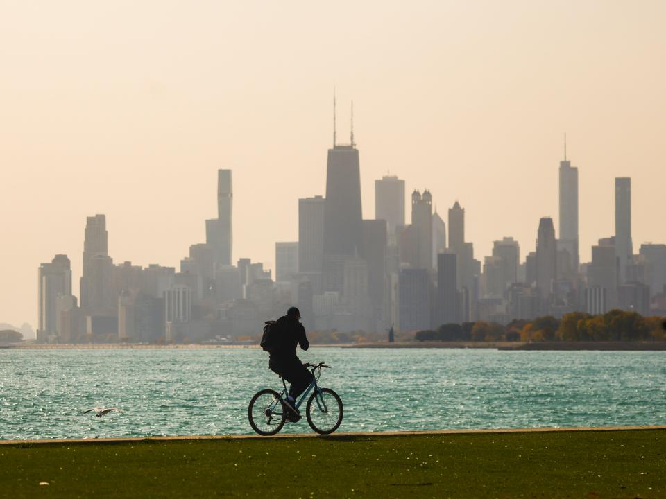 A cyclist seen biking on Chicago’s lakefront trail with the skyline in the background.