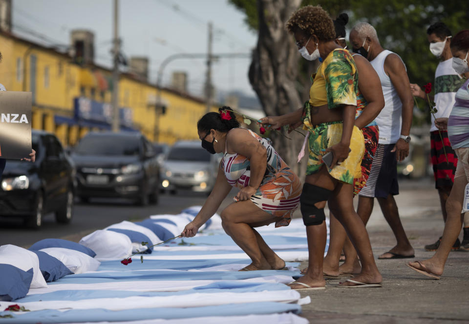 Residents place roses on mattresses symbolizing COVID-19 victims, during a protest against the Government's handling of the COVID-19 pandemic, organized by the Rio de Paz NGO, in front of the Ronaldo Gazolla hospital in Rio de Janeiro, Brazil, Wednesday, March 24, 2021. (AP Photo/Silvia Izquierdo)