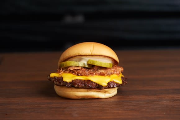 A cheeseburger placed in the middle of a brown tabletop