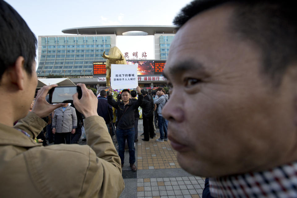 A man holds a billboard with slogans urging fights against terrorists on a square outside the Kunming Railway Station, where more than 10 assailants slashed scores of people with knives Saturday evening, in Kunming, in western China's Yunnan province, Monday, March 3, 2014. Twenty-nine slash victims and four attackers were killed and 143 people wounded in the attack which officials said was a terrorist assault by ethnic separatists from the far west. Chinese words on the billboard are, "The spring city under the shine, everybody beats the terrorists." (AP Photo/Alexander F. Yuan)