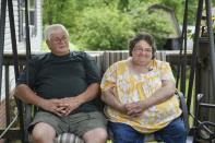 Doris Kelly, 57, sits with her husband, Tom Grimm, 62, on the front porch of their home on Monday, June 29, 2020 in Ruffs Dale, Pa. Kelly was one of the first patients in a UPMC trial for COVID-19. “It felt like someone was sitting on my chest and I couldn’t get any air,” Kelley said of the disease. (AP Photo/Justin Merriman)