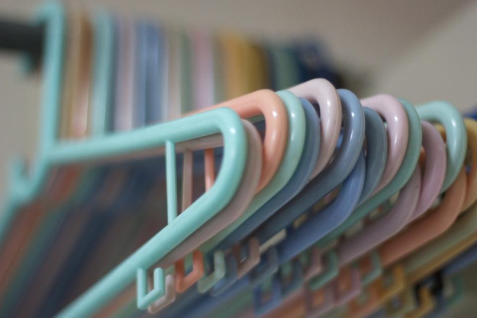 Pastel-colored plastic hangers hanging in closet 