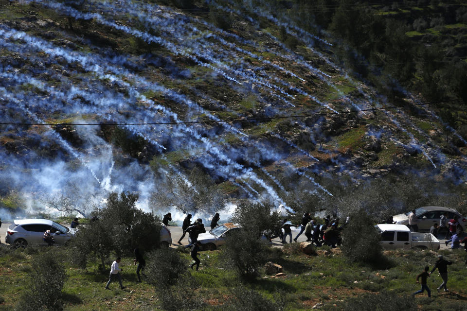 FILE - In this Feb. 28, 2020 file photo, Palestinian demonstrators run away from tear gas fired by Israeli forces during a protest against Israeli settlements and U.S. President Donald Trump's Mideast initiative, in the West Bank village of Beita near Nablus. Now that Prime Minister Benjamin Netanyahu has secured a new term in office, there’s little to prevent him from annexing large parts of the West Bank as early as this summer. Netanyahu has broad support in the new parliament and a friendly ally in the White House for his long-promised goal. Annexation, the likely death blow to faded Palestinian hopes for independence, will be high on the agenda of U.S. secretary of state Mike Pompeo’s blitz visit to Jerusalem next week. (AP Photo/Majdi Mohammed, File)