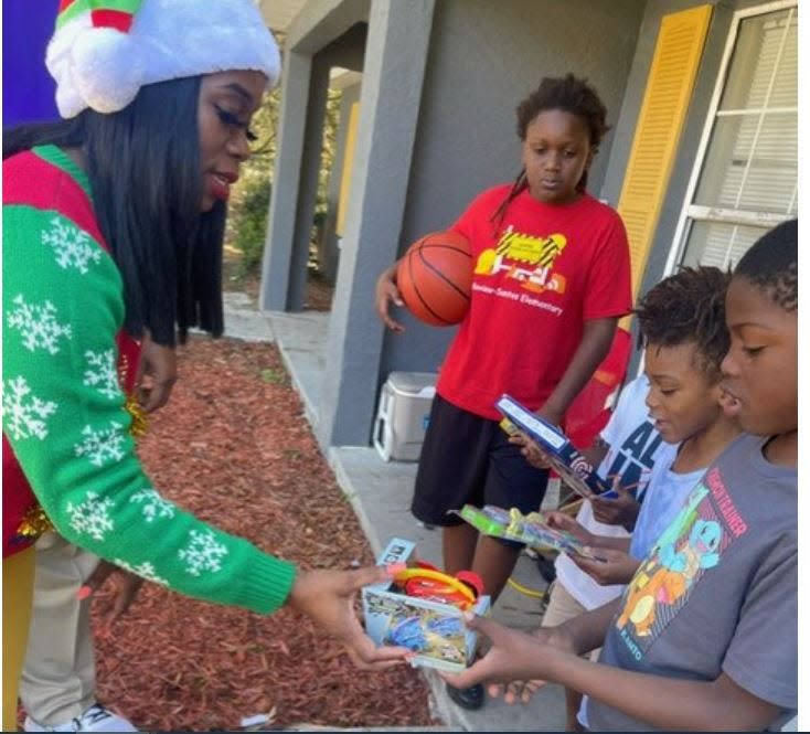Children receive Christmas presents from Danielle Wiggins of A Helping Hand Charity Outreach Inc. on Dec. 23 in Quail Run.