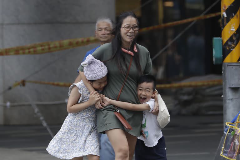 Una mujer y sus hijos batallan contra el viento generado por el tifón Haikui en Taipei, Taiwán,