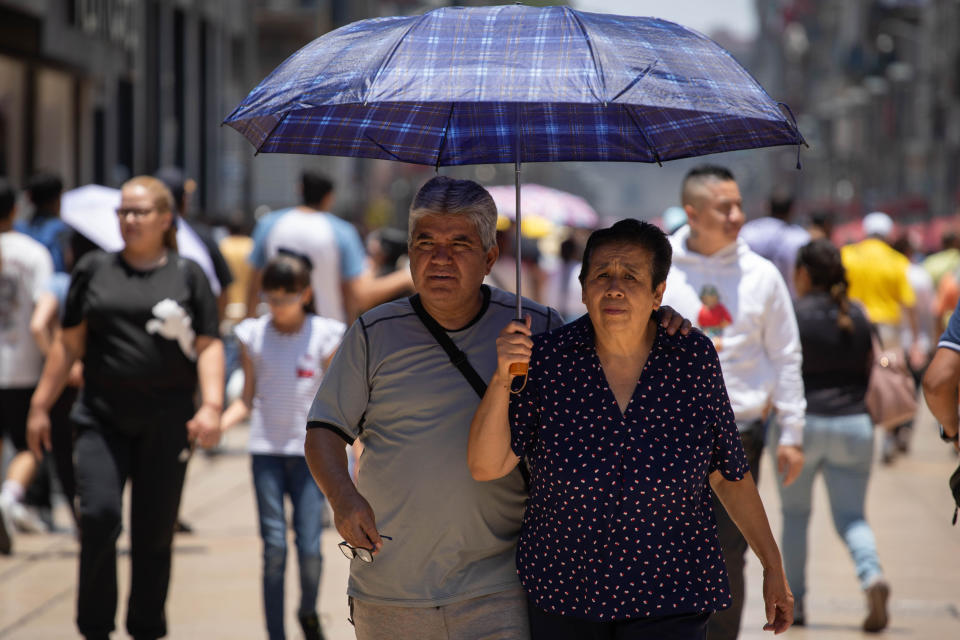 Una pareja se protege del sol con una sombrilla en México . (Daniel Cardenas/Anadolu via Getty Images)