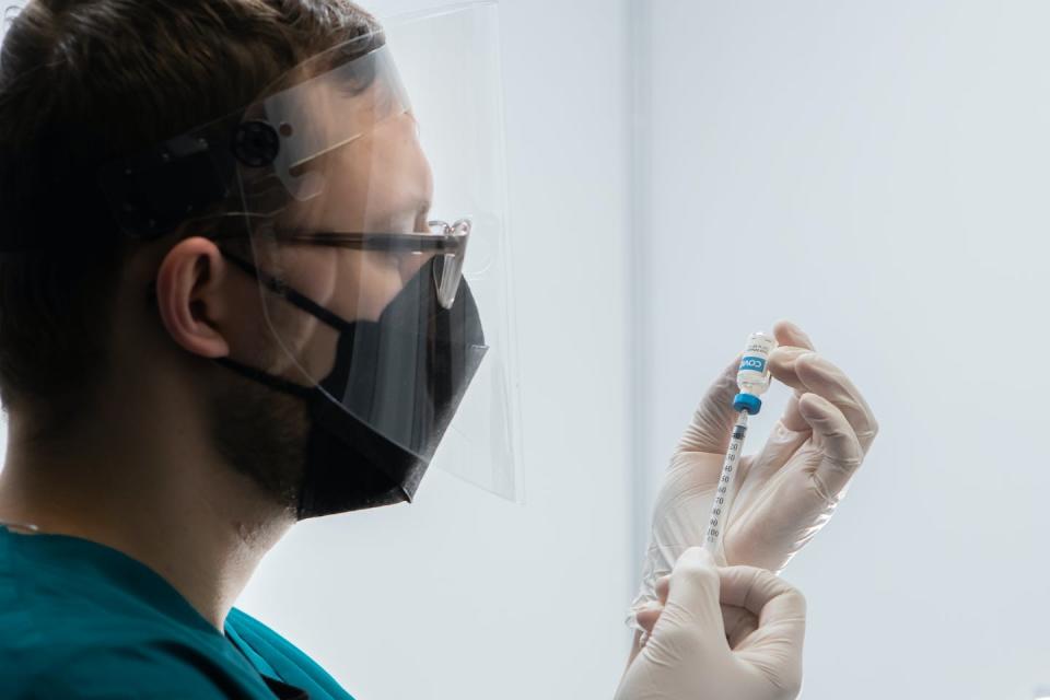 A male health-care worker draws up a vaccine.