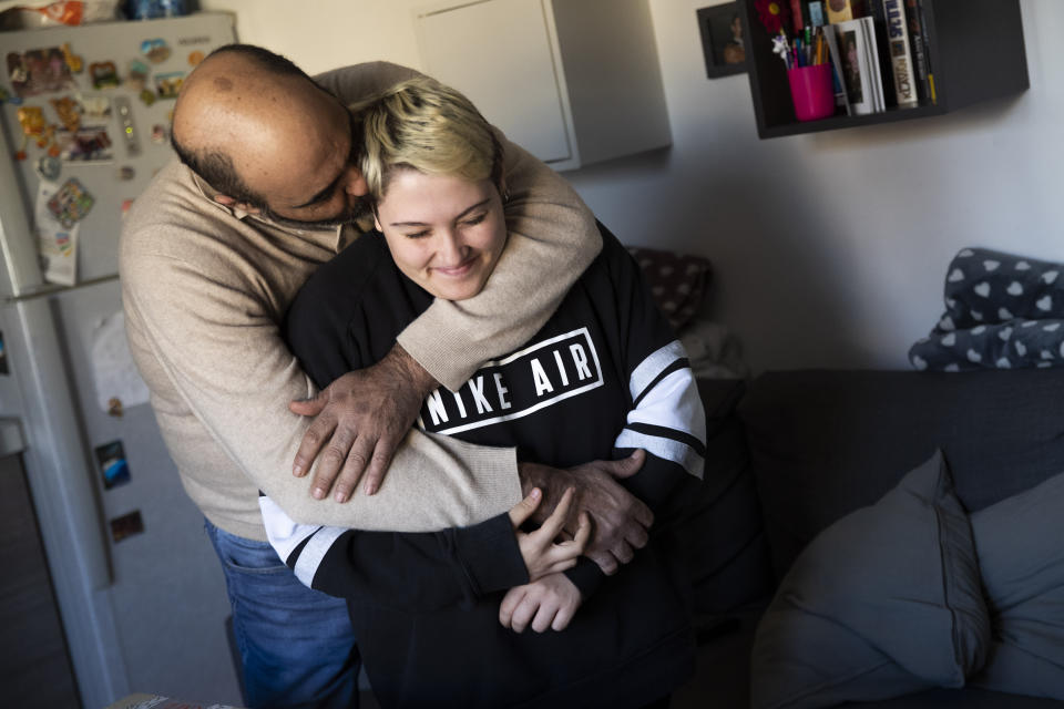 Matteo Coccimiglio is hugged by his father Franco in their kitchen in Rome, Saturday, March 20, 2021. Matteo is an 18-year-old student who identifies as a man and is in the process of changing his legal gender from female to male. The Ripetta school of art in Rome - where he studies - recently joined a handful of high schools in Italy that give transgender students the right to be known by a name other than the one they were given at birth. The initiative is meant to create an environment where transgender students feel secure and reflects a growing awareness in Italy of gender dysphoria among teenagers and children. (AP Photo/Alessandra Tarantino)