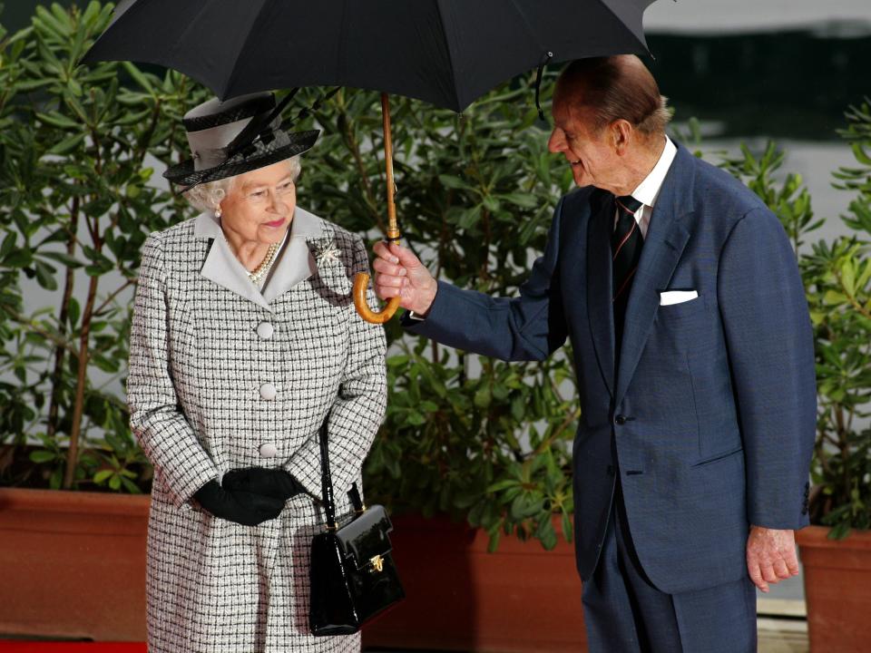 Prince Phillip holds an umbrella for Queen Elizabeth