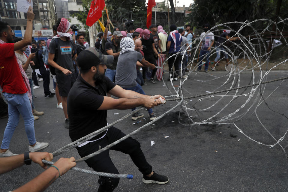 Hezbollah supporters and communist groups try to remove barbed wires that block a road leading to the U.S. embassy during a protest against American interference in Lebanon's affairs, in Aukar, northeast of Beirut, Lebanon, Friday, July 10, 2020. (AP Photo / Hussein Malla)