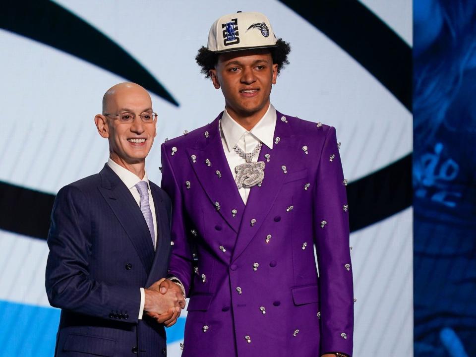 Paolo Banchero shakes Adam Silver's hand and poses at the NBA draft.