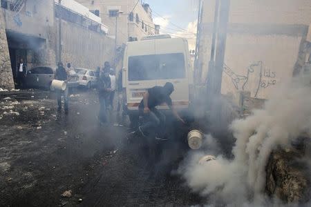 Palestinians try to stop a tear gas canister from emitting more gas during clashes with Israeli police in the Abu Tor neighbourhood of east Jerusalem October 30, 2014. REUTERS/Ammar Awad