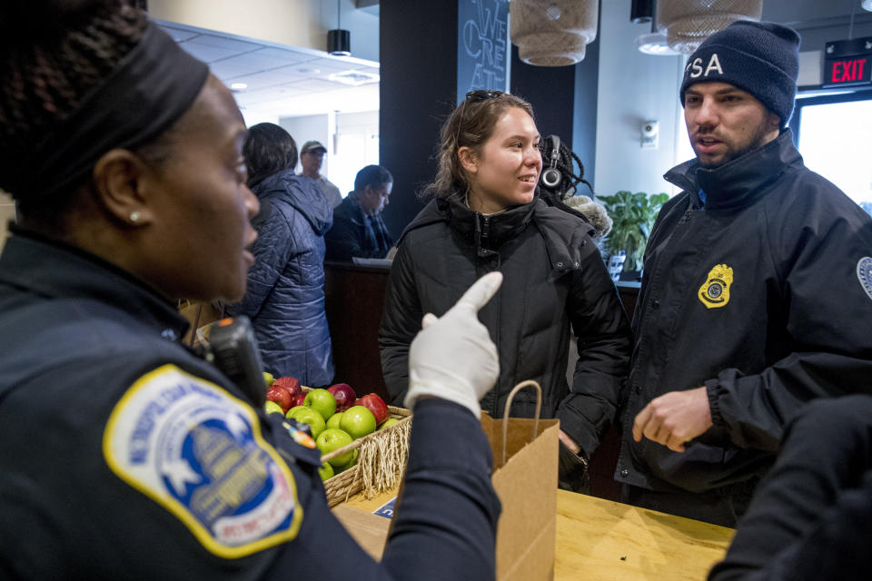 Metropolitan Police Officer and volunteer Adriane Benson, left, takes a food order for Shane Smith, a TSA agent, right, as he and other furloughed government workers affected by the shutdown receive free food and supplies at World Central Kitchen, the not-for-profit organization started by Chef Jose Andres, Tuesday, Jan. 22, 2019 in Washington. The organization devoted to providing meals in the wake of natural disasters, has set up a distribution center just blocks from the U.S. Capitol building to assist those affected by the government shutdown. (AP Photo/Andrew Harnik)