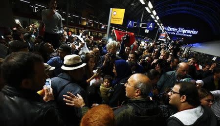 Wellwishers surround a family of migrants from Syria (at C, man in hat and woman with baby) arriving with a train from Vienna at the railway station in Frankfurt, Germany, September 5, 2015. REUTERS/Kai Pfaffenbach