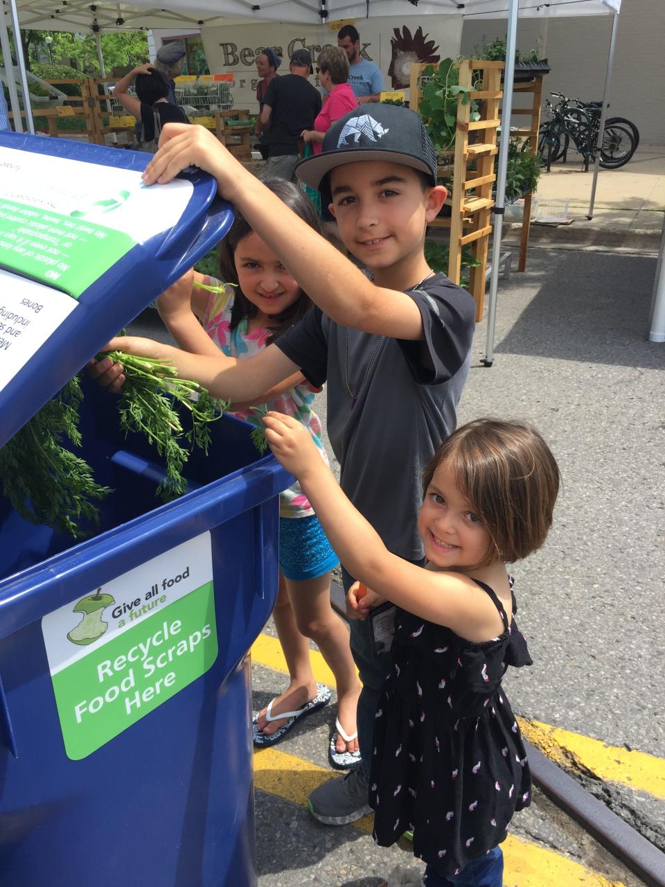 A group of kids drops off food scraps at one of the compost bins available during the Downtown Petoskey Farmers Market.