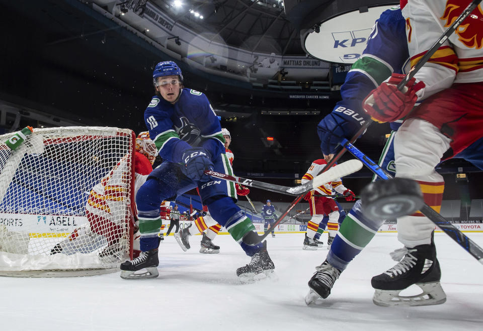 Vancouver Canucks' Jake Virtanen (18) and Calgary Flames' Josh Leivo, front right, vie for the puck as goalie Jacob Markstrom, back left, of Sweden, watches during the first period of an NHL hockey game Saturday, Feb. 13, 2021, in Vancouver, British Columbia. (Darryl Dyck/The Canadian Press via AP)