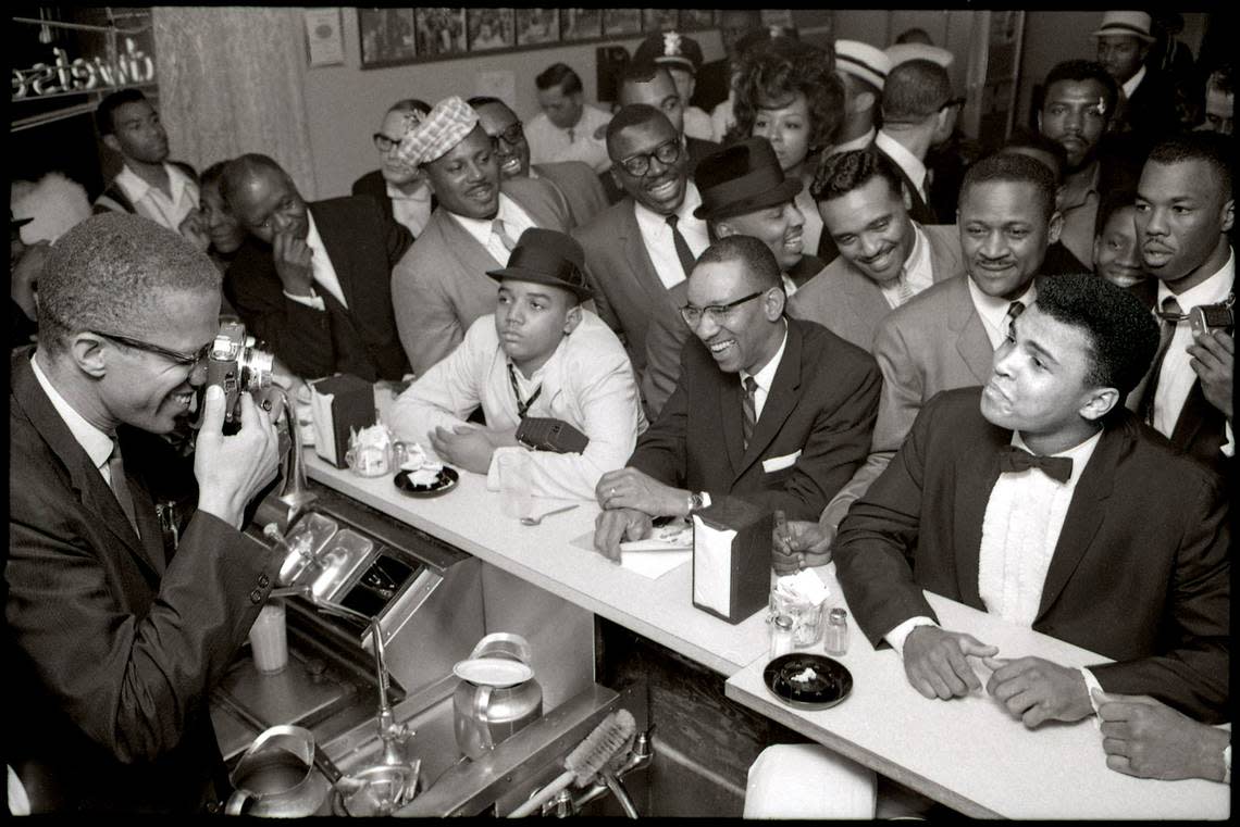 Malcolm X trains his camera on Cassius Clay, sitting at the counter of Miami s Hampton House in 1964, surrounded by fans after he beat Sonny Liston for the heavyweight championship of the world title on Feb. 25, 1964, in Miami Beach. The next day, Clay announced he had become a member of the Nation of Islam and changed his name to Muhammad Ali.