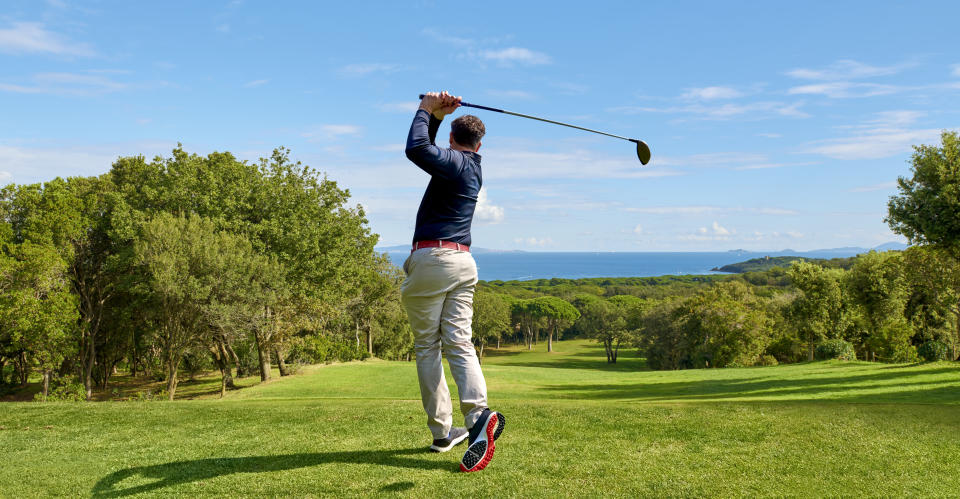 Golfer on a professional golf course. Golfer with golf club hitting the ball for the perfect shot.