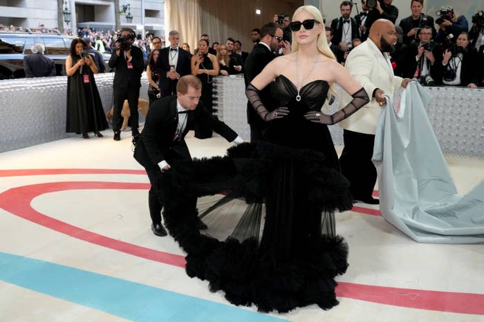 Jessica Chastain at the Met Gala as someone adjusts her chiffon gown train