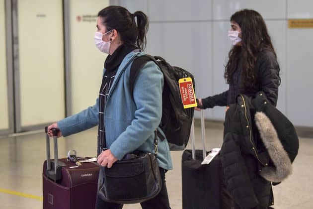 Passengers wear masks as a precautionary measure against the new coronavirus as they travel Wednesday through Guarulhos International Airport in Sao Paulo, Brazil.