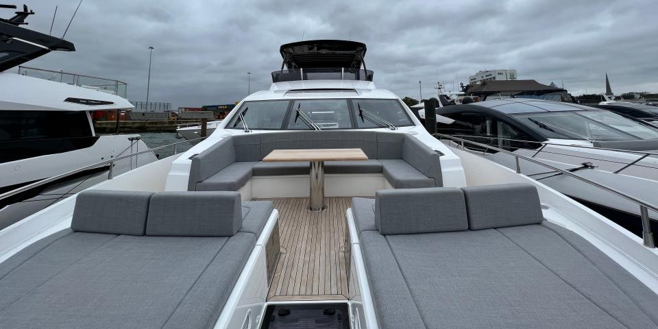 A u-shaped booth and two sunloungers in grey cushions at the bow of a Sunseeker 76 