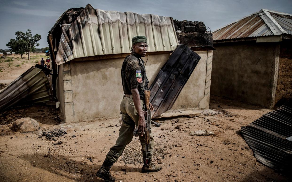 A Nigerian Police Officer patrols an area of destroyed and burned houses after a recent Fulani attack in the Adara farmers' village of Angwan Aku - AFP