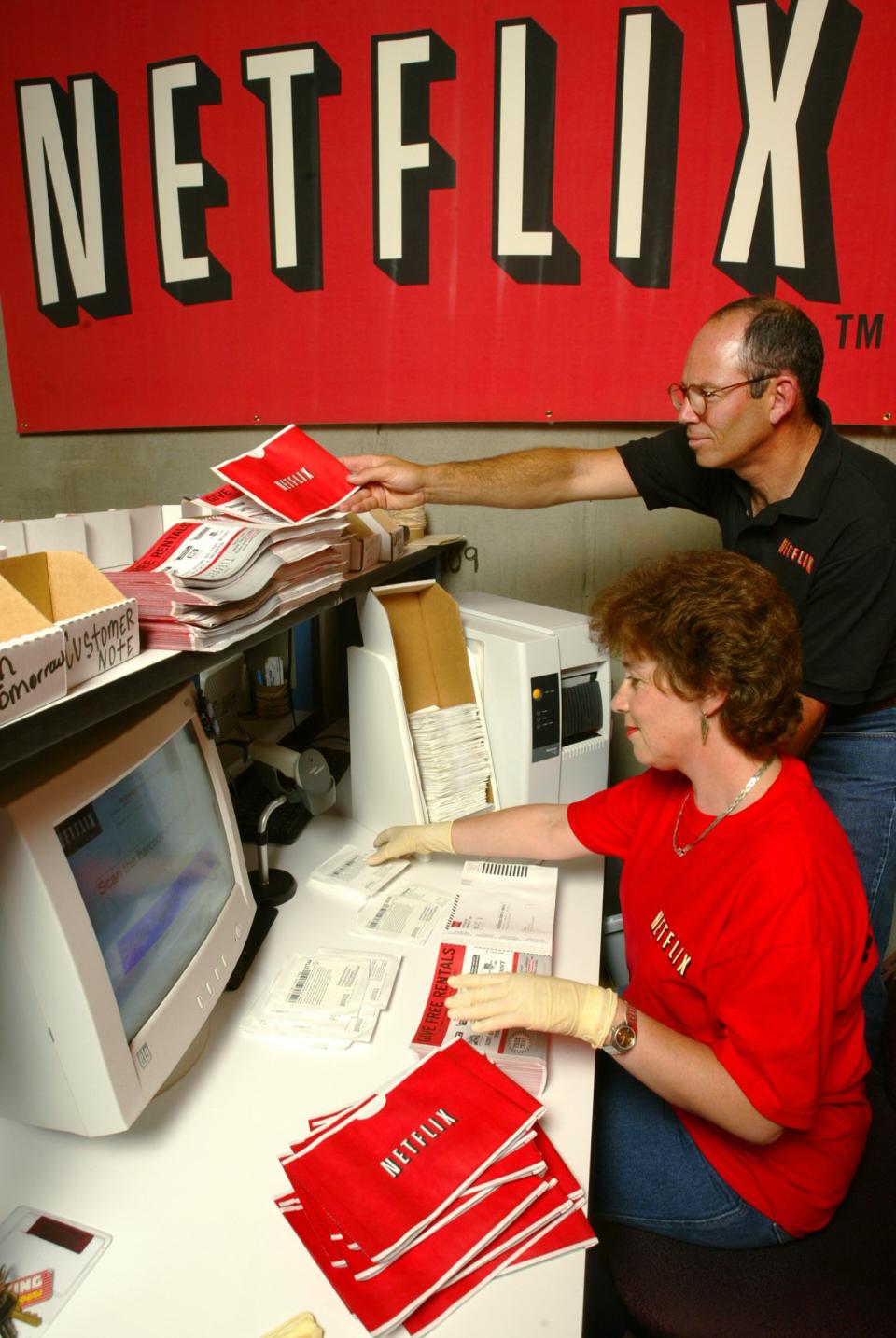 FILE - In this July 11, 2002, file photo, Netflix co-founder Marc Randolph looks over the shoulder of Natalya Kontorovich at Netflix Inc.'s Denver distribution site. A new book,"Netflixed: The Epic Battle for America's Eyeballs," is set to go on sale Thursday, Oct. 11, 2012. The book tries to debunk a widely told tale about the company's origins and paints a polarizing portrait of its star CEO Reed Hastings. (AP Photo/Netflix, Jack Dempsey)