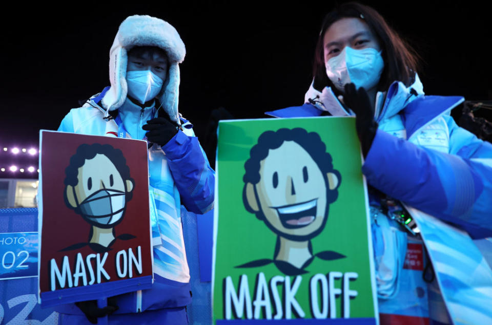 Volunteers carry signs to give visual signals allowing the medallists to take off their masks during the women's moguls victory ceremony at the Medal Plaza on Feb. 7, 2022, as part of the 2022 Winter Olympic Games.<span class="copyright">Sergei BobylevTASS via Getty Images</span>