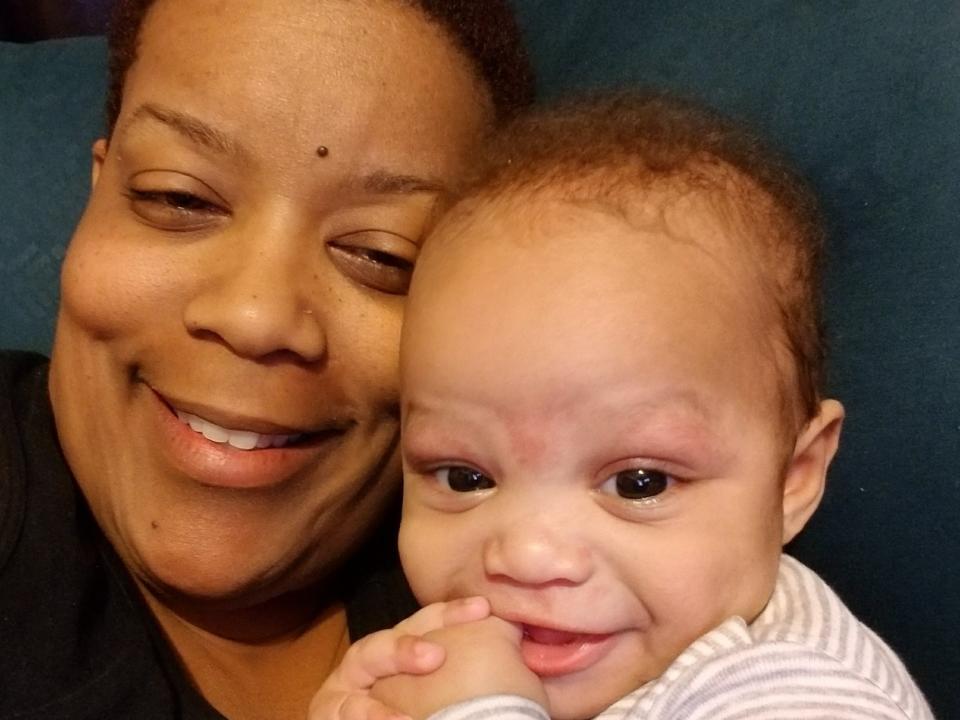 A close-up picture of a smiling woman and a baby.