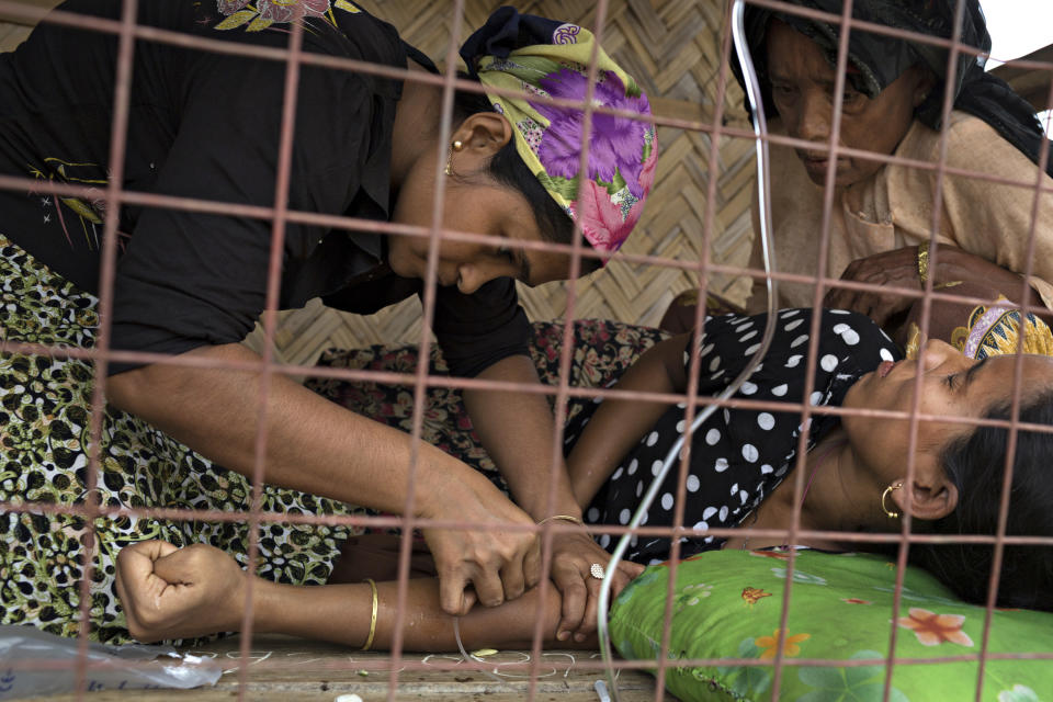 SITTWE, BURMA - MAY 06: An assistant sets up an IV at a makeshift clinic and pharmecy in the Thet Kae Pyin refugee camp on May 6, 2014 in Sittwe, Burma. Some 150,000 Rohingya IDP (internally displaced people) are currently imprisoned in refugee camps outside of Sittwe in Rakhine State in Western Myanmar. Medecins Sans Frontieres (MSF), the primary supplier of medical care within the camps, was banned in March by the Myanmar government. Follow up attacks by Buddhist mobs on the homes of aid workers in Sittwe put an end to NGO operations in the camps. Though some NGOs are beginning to resume work, MSF remains banned, and little to no healthcare is being provided to most Rohingya IDPs. One Rohingya doctor is servicing 150,000 refugees with limited medication. Several Rakhine volunteer doctors sporadically enter the camps for two hours a day. Births are the most complicated procedures successfully carried out in the camps, requests to visit Yangon or Sittwe hospitals for life threatening situations require lengthy applications and are routinely denied. Malnutrition and diarrhea are the most widespread issues, but more serious diseases like tuberculosis are going untreated and could lead to the rise of drug resistant tuberculosis (DR-TB).  (Photo by Andre Malerba/Getty Images)