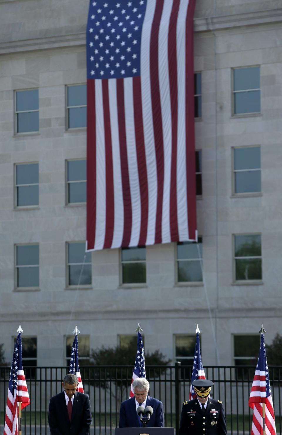 (L-R) U.S. President Barack Obama, Secretary of Defense Chuck Hagel, and Chairman of the Joint Chiefs of Staff U.S. Army General Martin Dempsey attend remembrance ceremonies for 9/11 at the Pentagon 9/11 Memorial in Washington September 11, 2013. The large flag in background marks the point of impact where a jetliner crashed into the Pentagon 12 years ago today. (REUTERS/Gary Cameron)