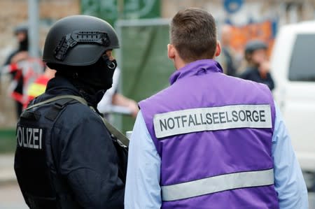 A police officer speaks with a member of the emergency pastoral care near the site of a shooting in Halle