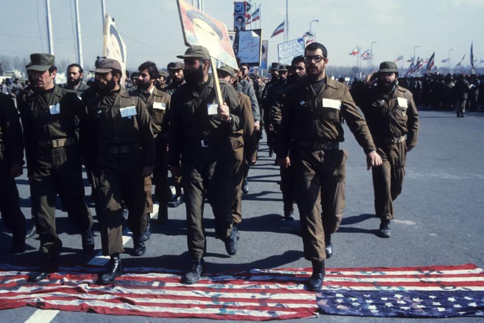 <div class="inline-image__caption"><p>Revolutionary Guards in green uniforms march over a U.S. flag spread on the tarmac in Azadi square, Tehran, whilst carrying banners with photos of Ayatollah Khomeini on the third anniversary of the Islamic Revolution, Feb. 11, 1982. </p></div> <div class="inline-image__credit">Kaveh Kazemi/Getty</div>