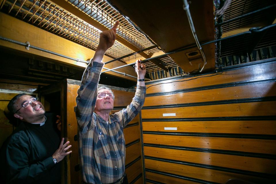 Tom Engman, of Sheboygan, right, points out a row of actuators mechanism in the air chest for the organ at Holy Name Catholic Church to Associate Pastor Norberto Jose Sandoval, Tuesday, March 14, 2023, in Sheboygan, Wis.