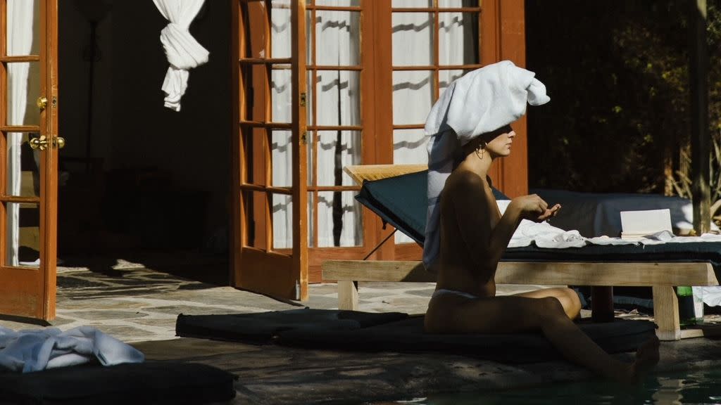 a bride to be sits beside the pool with an enormous towel on her head