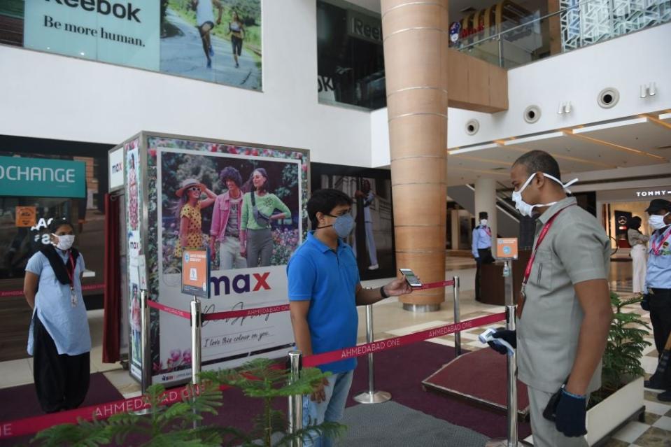 A member of the internal medical team checks the Aarogya Setu app on the mobile phone of a staff at the entrance of the Ahmedabad One Mall (AFP via Getty Images)