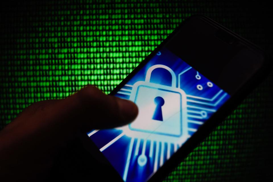 POLAND - 2019/02/17: In this photo illustration, the CYber lock symbol is seen displayed on an Android mobile phone with hacker code in the background.