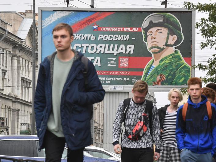 Young men walk past the billboard in the Russian city (AFP via Getty Images)