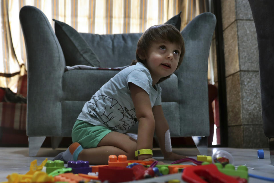 CORRECTS THE FAMILY NAME OF THE BOY - Three-year-old Abed Itani, plays with toys at his family house in Beirut, Lebanon, Tuesday, Aug. 11, 2020. Abed was playing with his Lego blocks when the huge blast ripped through Beirut, shattering the nearby glass doors. He had cuts on his tiny arms and feet, a head injury, and was taken to the emergency room, where he sat amid other bleeding people. (AP Photo/Bilal Hussein)