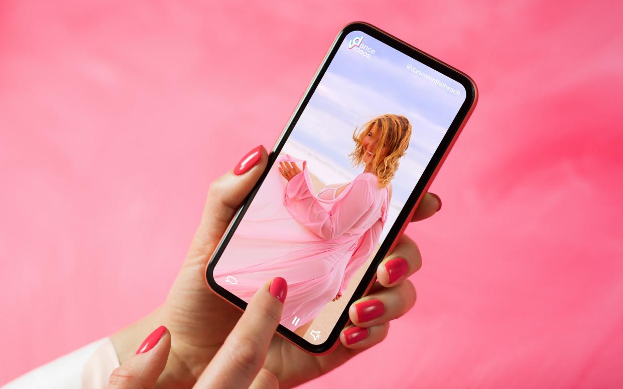 Person holding phone and looking at woman dancing in video posted on social media - Getty Images/iStockphoto