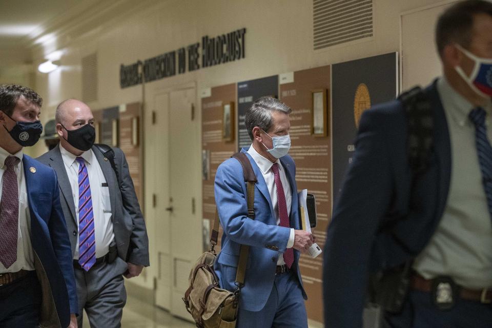 Georgia Gov. Brian Kemp, second from right, leaves the Georgia State Capitol Building after he signed into law a sweeping Republican-sponsored overhaul of state elections that includes new restrictions on voting by mail and greater legislative control over how elections are run, Thursday, March 25, 2021 in Atlanta. (Alyssa Pointer/Atlanta Journal-Constitution via AP)