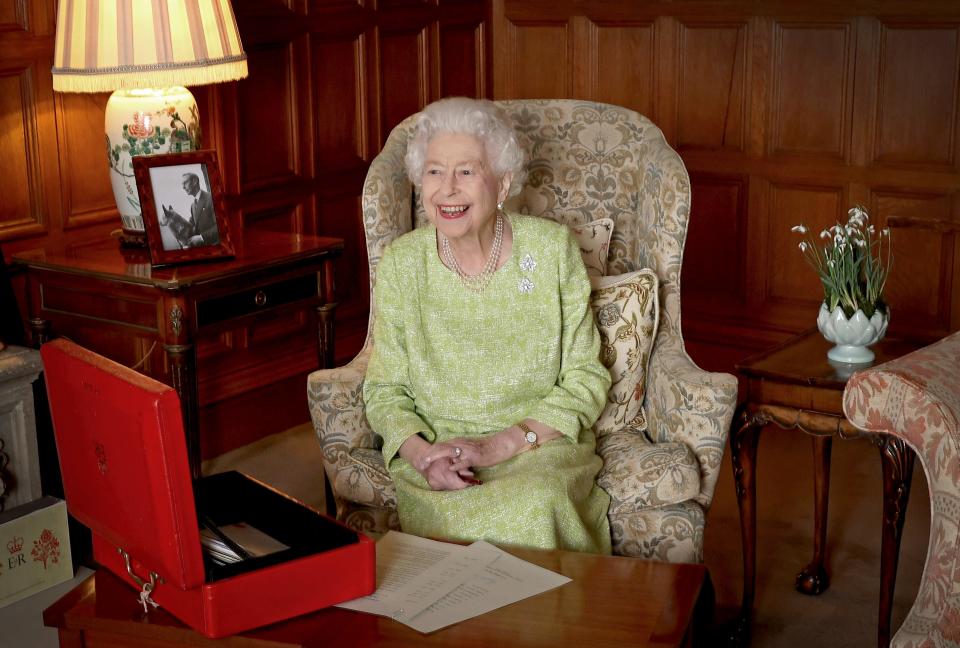 Queen Elizabeth II sits in the Saloon at Sandringham with one of her red despatch boxes of government papers, with a picture of her father, King George VI, by her side.