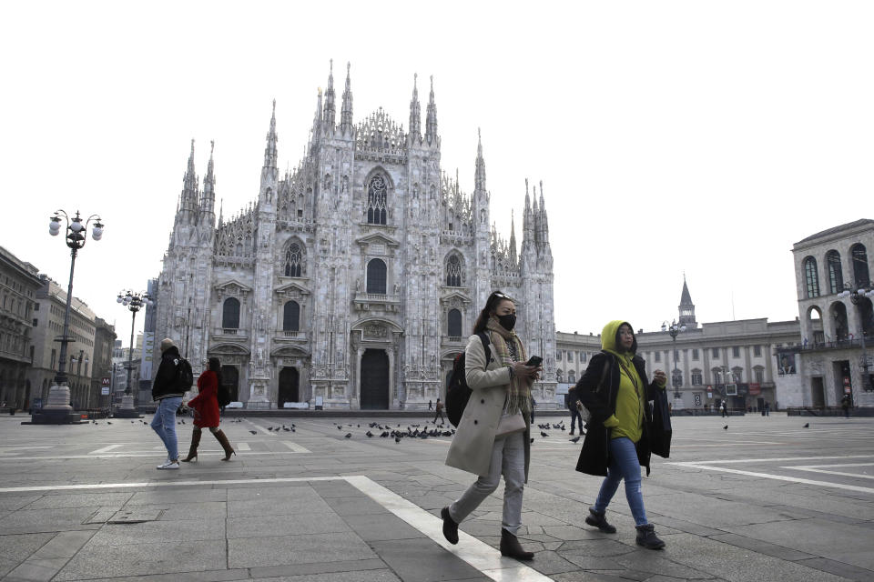 FILE - In this Sunday, Feb. 23, 2020. file photo, a woman wearing a sanitary mask walks past the Duomo gothic cathedral in Milan, Italy. The focal point of the coronavirus emergency in Europe, Italy, is also the region's weakest economy and is taking an almighty hit as foreigners stop visiting its cultural treasures or buying its prized artisanal products, from fashion to food to design. Europe’s third-largest economy has long been among the slowest growing in the region and is the one that is tallying the largest number of virus infections outside Asia. (AP Photo/Luca Bruno, File)