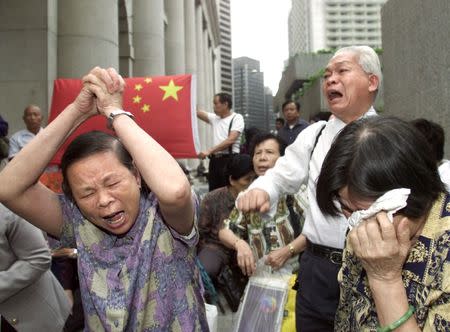 Hong Kong relatives of Chinese migrants cry after being expelled from a park in central Hong Kong, April 25, 2002. The residency issue flared up in 2002 when Hong Kong began deporting some 4,000 mainland Chinese who lost legal battles to stay in the territory. So-called "abode seekers" and their supporters staged protests, including surrounding the car of the island's security chief Regina Ip. REUTERS/Kin Cheung/File photo