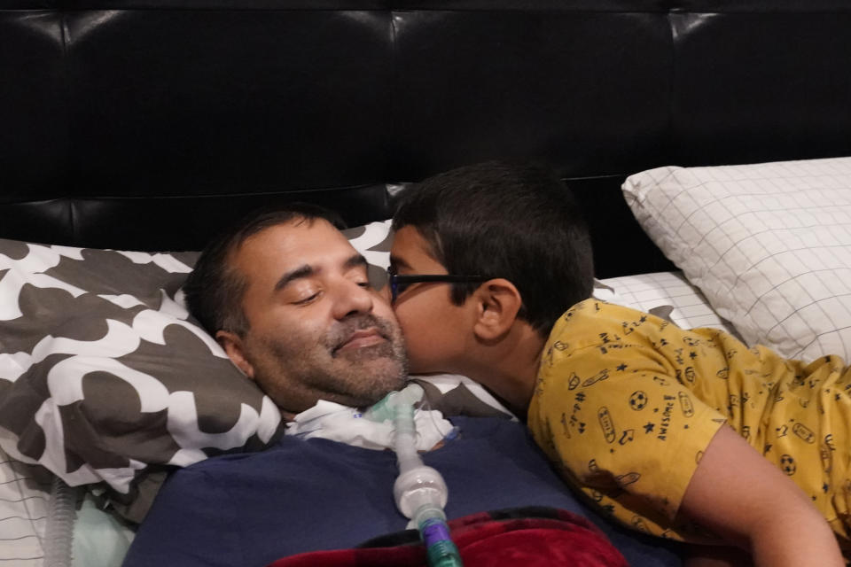 Keaton Koyita, 9, kisses his father Rupesh Kotiya after he helped prepare him for bed at their home in Plano, Texas, Friday, April 8, 2022. Millions of Americans with serious health problems depend on children ages 18 and younger to provide some or all of their care at home. An exact number is hard to pin down, but researchers think millions of children are involved in caregiving in the U.S. (AP Photo/LM Otero)