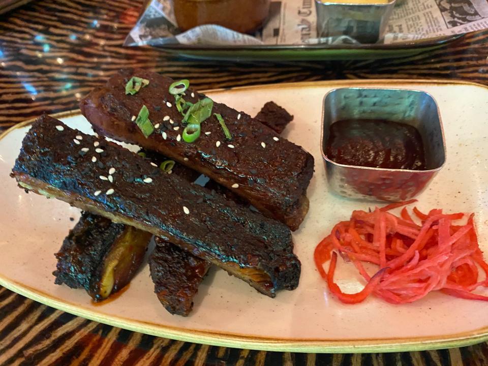 Smoked pork ribs arranged on plate with pickled vegetable and a dipping sauce