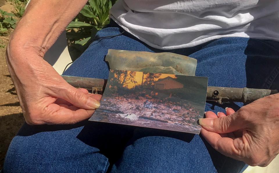 Cheri Skipper, a Harbison Canyon resident, holds her burned flute and a picture showing what her home looked like after it burned during the Cedar Fire in 2003.