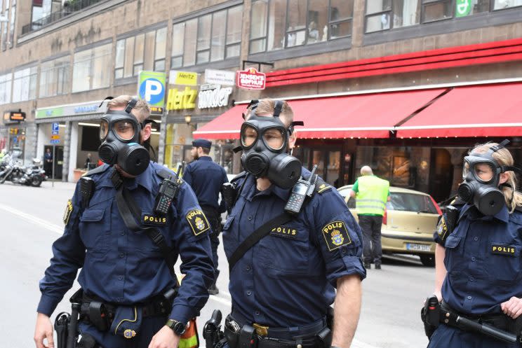 Officers in gas masks attend the scene (Rex Features)