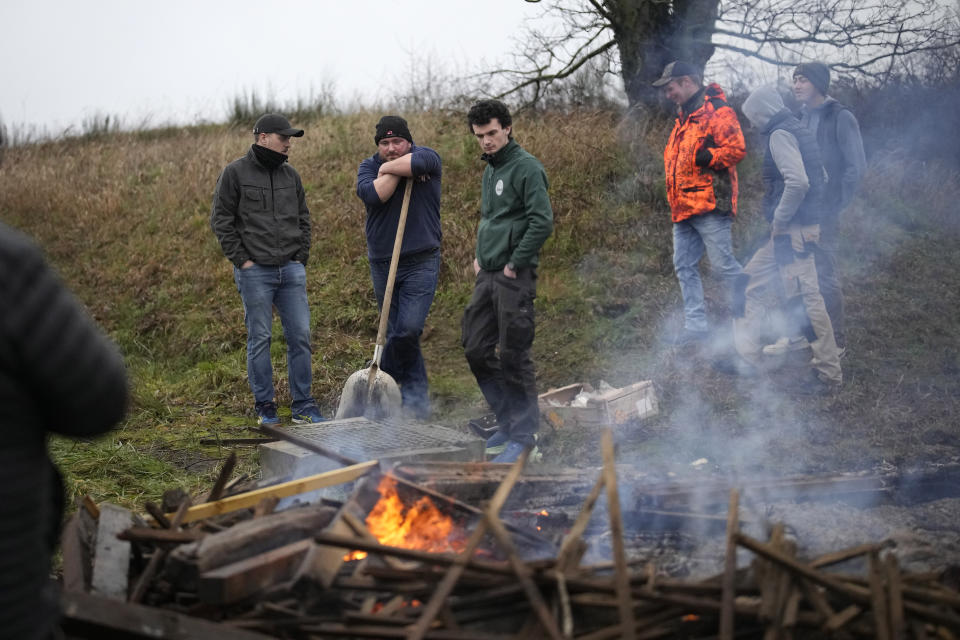 Farmers rest at a bonfire a they block a highway leading to Paris, Friday, Jan. 26, 2024 in Saclay, south of Paris. Snowballing protests by French farmers crept closer to Paris with tractors driving in convoys and blocking roads in many regions of the country to ratchet up pressure for government measures to protect the influential agricultural sector from foreign competition, red tape, rising costs and poverty-levels of pay for the worst-off producers. (AP Photo/Christophe Ena)